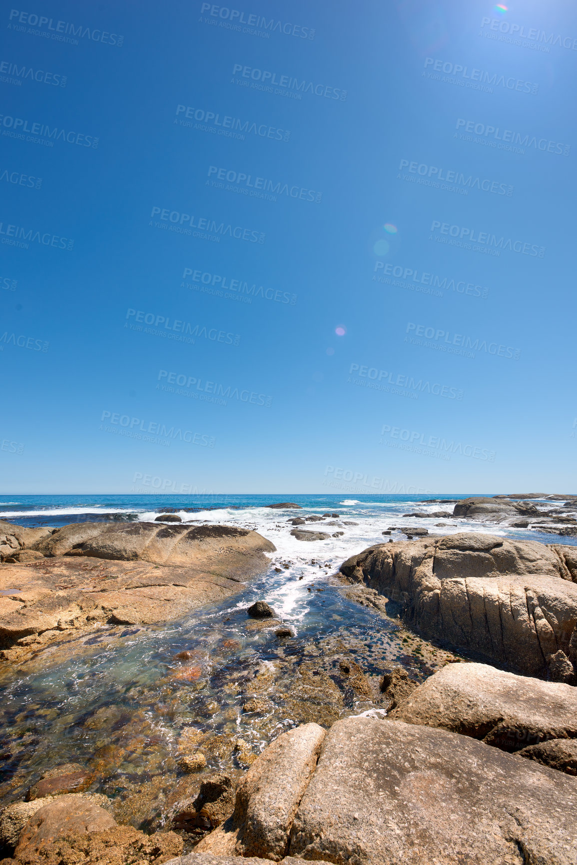 Buy stock photo Big rocks in the ocean under a clear blue sky with copy space. Beautiful landscape of beach waves, tides and currents flowing through boulders and big stones in the sea on a calm, bright summer day