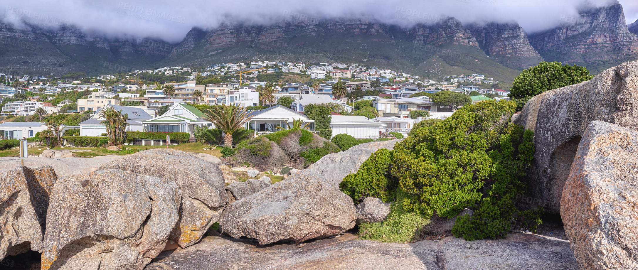 Buy stock photo Rocks and boulders against a majestic mountain and cityscape background with lush green plants and coulds. Remote and quiet landscape on a cliff with stones to enoy a urban view with private homes