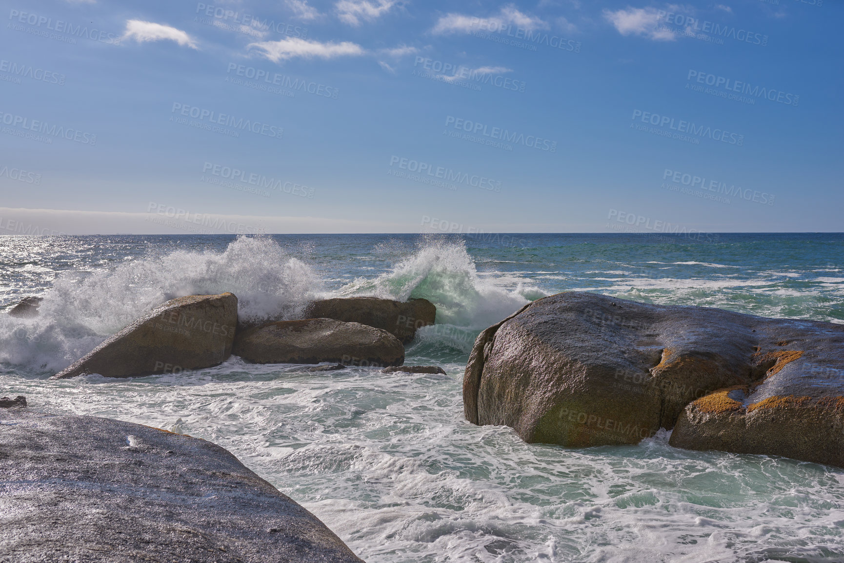 Buy stock photo A beautiful coastline with waves and rocks in the sea on a sunny, beach day. An ocean view of the water and a blue sky background in summer. Outdoor scenery of a relaxing seaside landscape in nature.