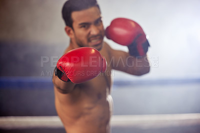 Buy stock photo Cropped portrait of a handsome young male boxer striking towards the camera during a fight in the ring