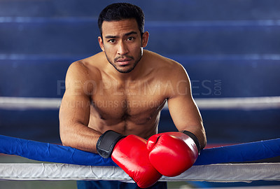 Buy stock photo Cropped portrait of a handsome young male boxer leaning against the ropes after a fight in the ring