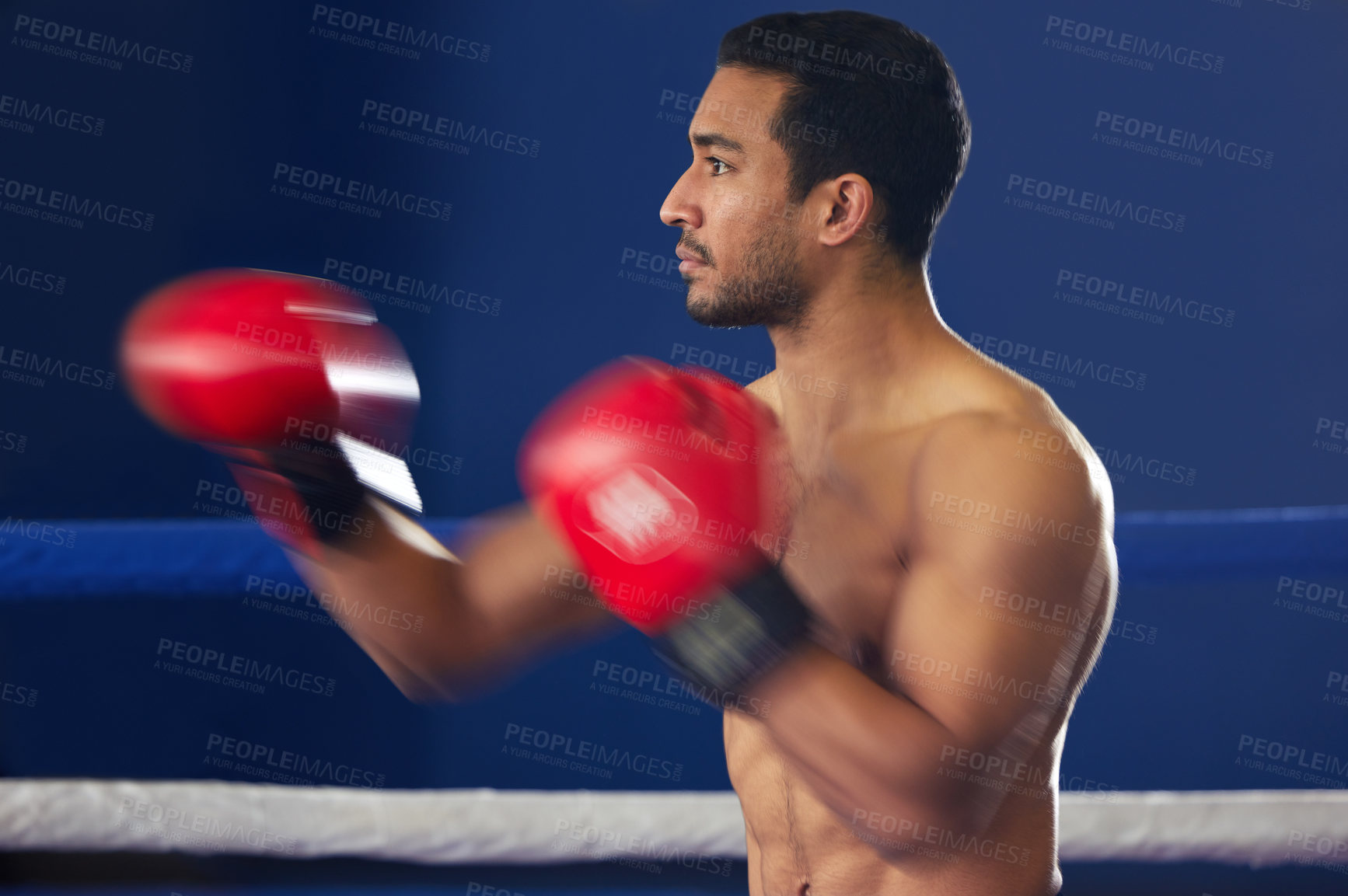 Buy stock photo Cropped shot of a handsome young male boxer striking swiftly during a fight in the ring