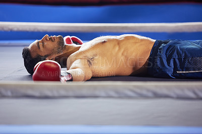 Buy stock photo Cropped shot of a handsome young male boxer lying in the ring with his eyes closed after a fight