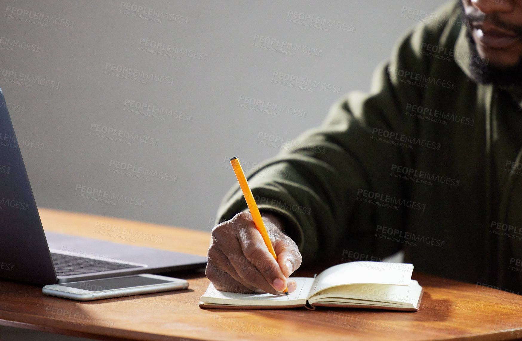 Buy stock photo Shot of an unrecognizable man writing in a notebook in an office
