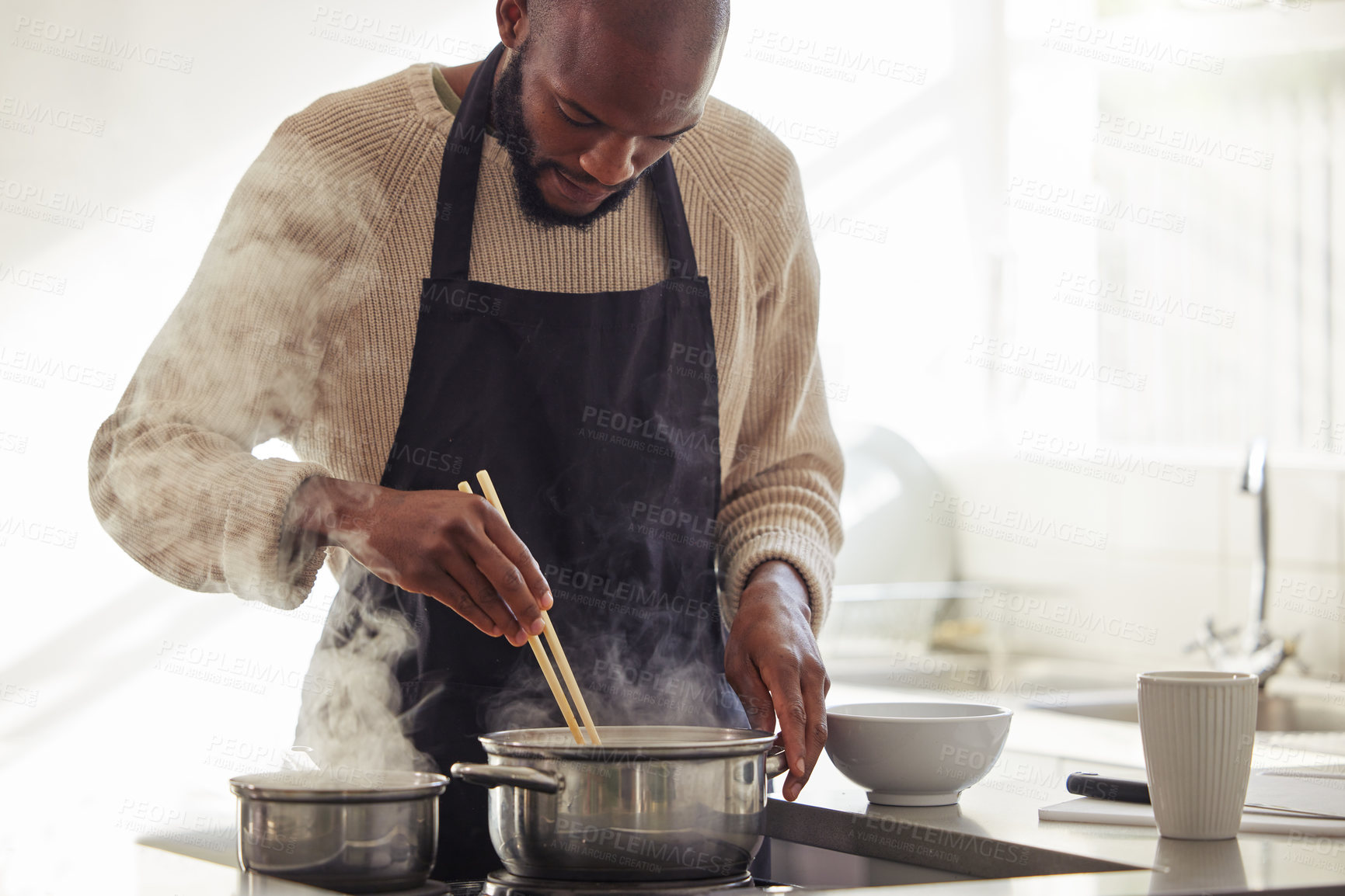 Buy stock photo Man, cooking and pot with steam in the home for lunch or dinner, busy and hungry for food with preparation. Catering, African chef with chopsticks for Asian cuisine and meal with nutrition in kitchen