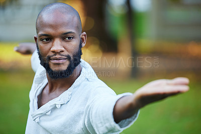 Buy stock photo Cropped shot of a handsome young man practicing yoga outside in the park