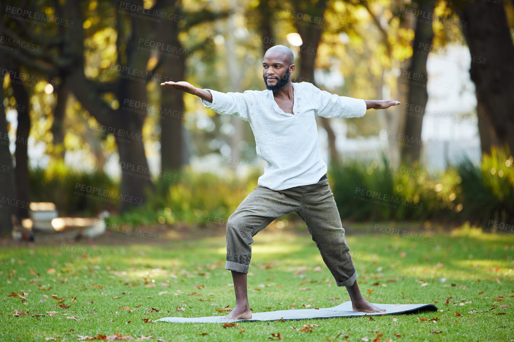 Buy stock photo Full length shot of a handsome young man practicing yoga outside in the park