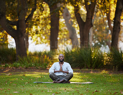 Buy stock photo Full length shot of a handsome young man meditating while practicing yoga outside at the park