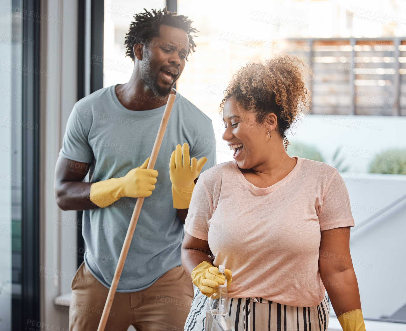 Buy stock photo Shot of a young couple singing while cleaning at home