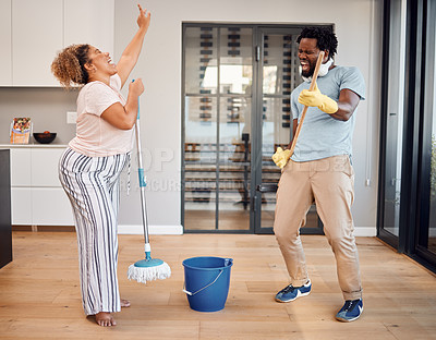 Buy stock photo Shot of a young couple singing and dancing while cleaning at home