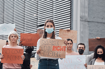 Buy stock photo Cropped portrait of an attractive young woman holding up a sign protesting against the covid 19 vaccine with other demonstrators in the background