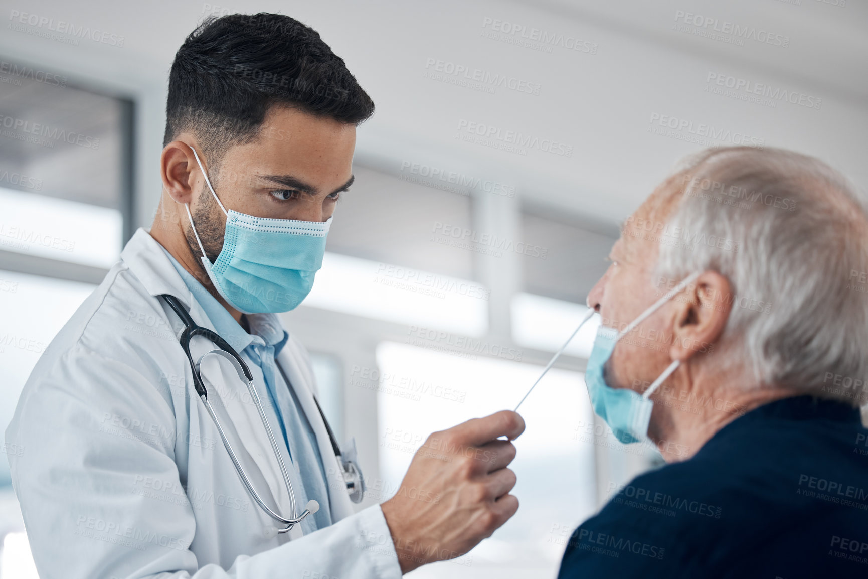 Buy stock photo Cropped shot of a handsome young male doctor testing a senior patient for covid
