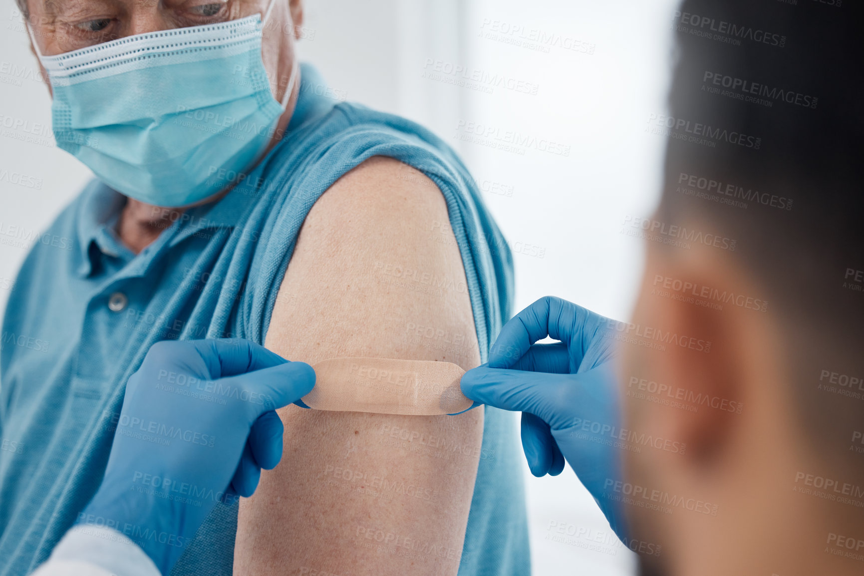 Buy stock photo Cropped shot of an unrecognizable male doctor placing a plaster on a senior patient's arm after giving him the covid 19 vaccine