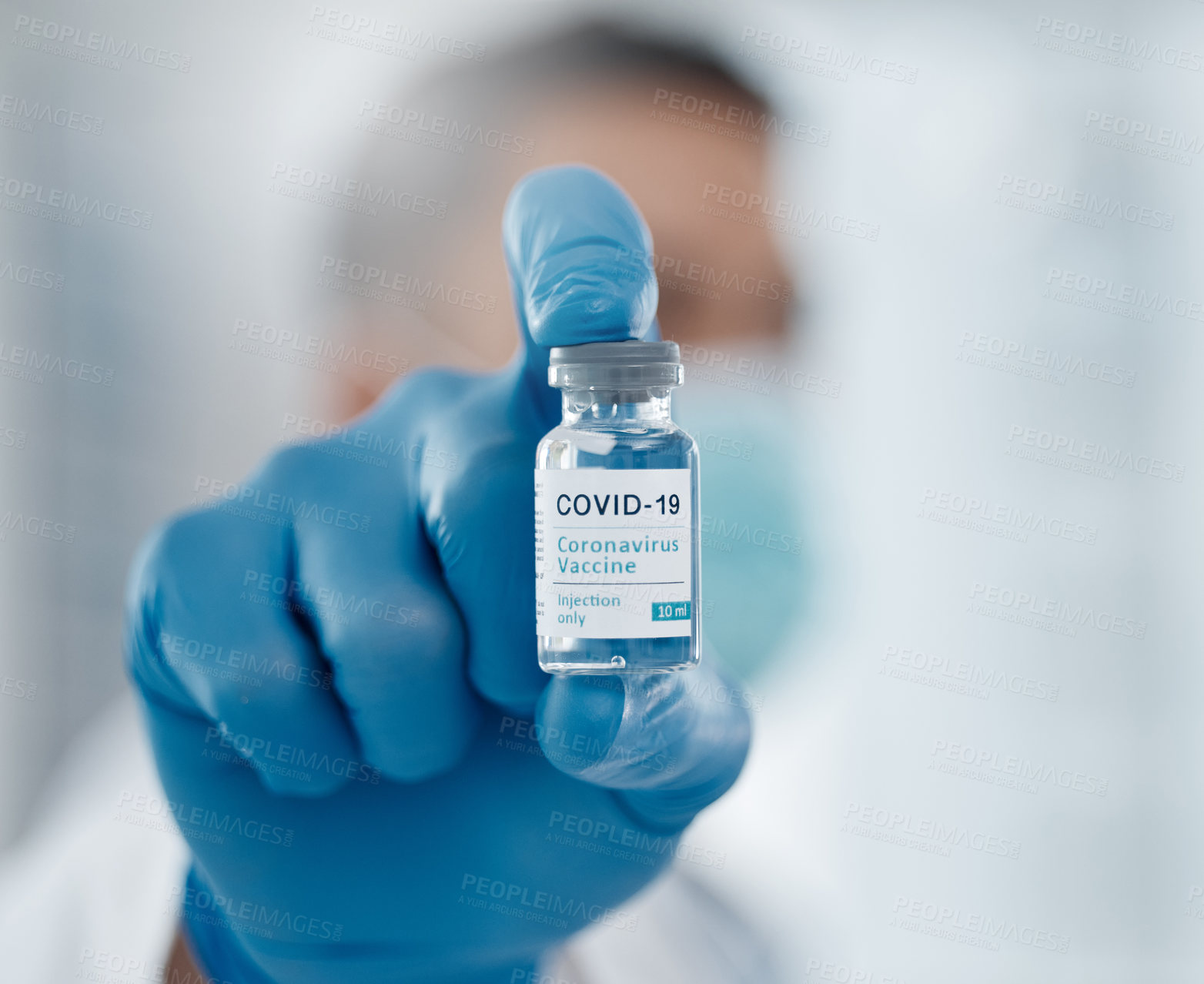Buy stock photo Closeup shot of a bottle of covid 19 vaccine being held towards the screen by an unrecognizable male doctor