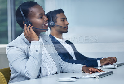 Buy stock photo Cropped shot of two young call center agents working at their desks in the office