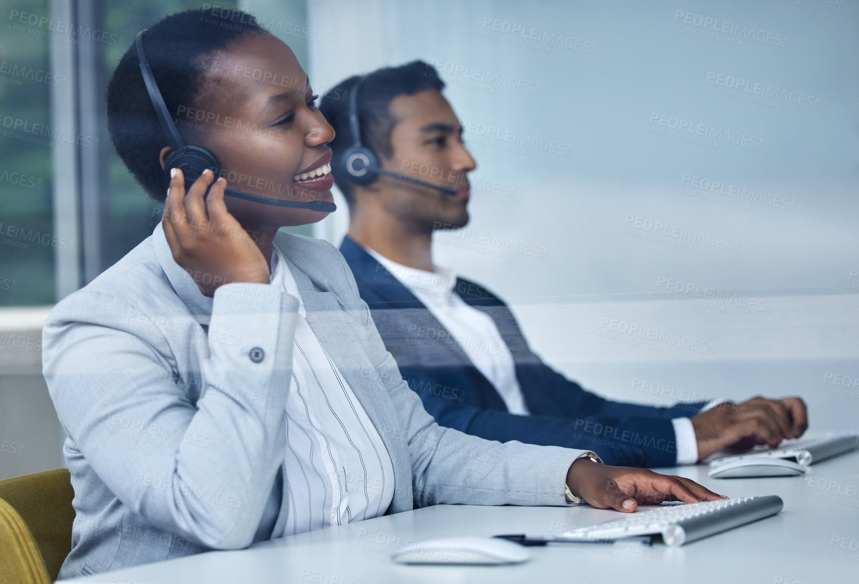 Buy stock photo Cropped shot of two young call center agents working at their desks in the office