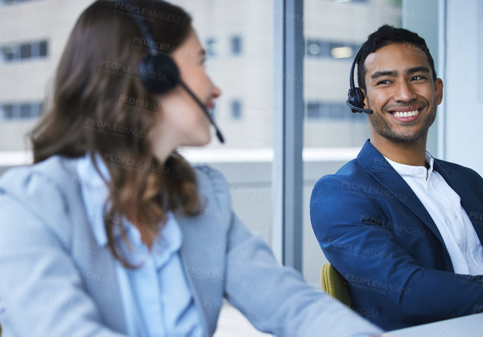 Buy stock photo Cropped shot of two young call center agents working at their desks in the office