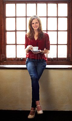 Buy stock photo Smiling young woman perched on a windowsill and enjoying a cup of coffee - portrait
