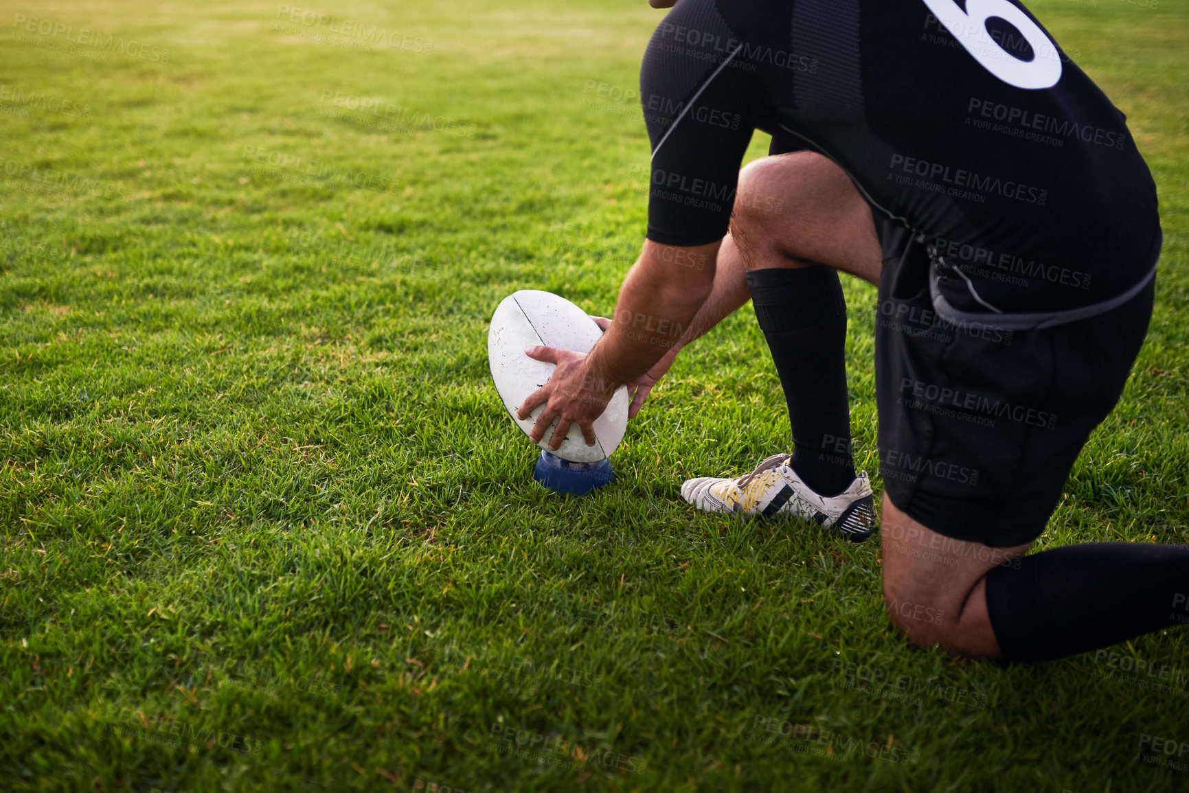 Buy stock photo Cropped shot of an unrecognizable sportsman crouching alone during rugby practice in a sports club