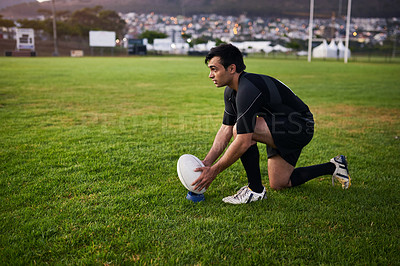 Buy stock photo Full length shot of a handsome young sportsman crouching alone during rugby practice in a sports club
