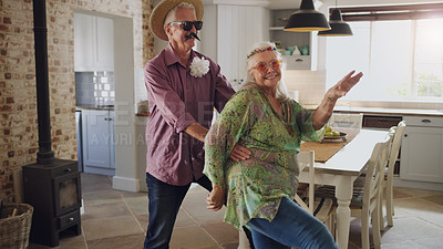 Buy stock photo Shot of a happy senior couple feeling playful and wearing costumes while dancing around their house