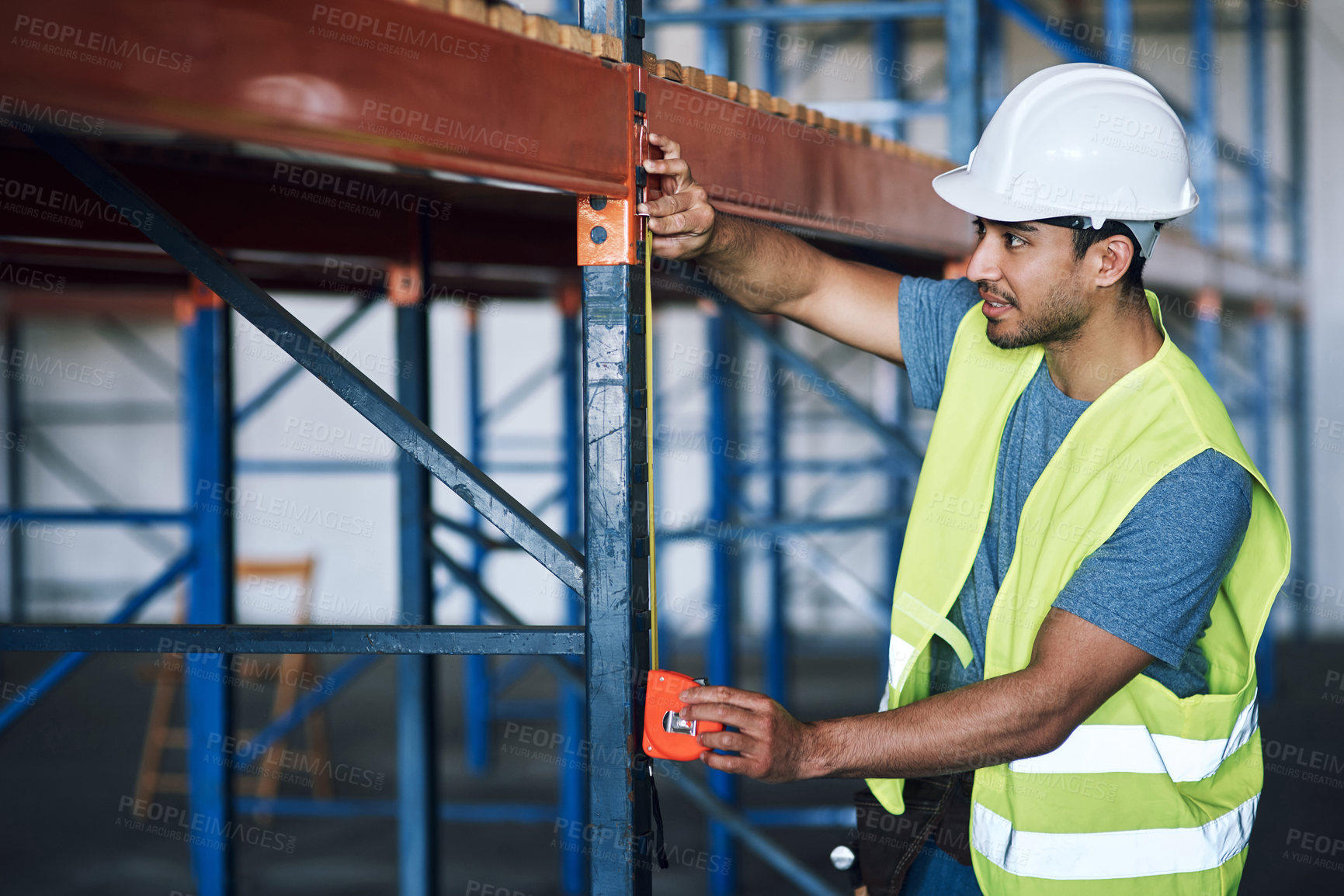 Buy stock photo Shot of a young builder using a measuring tape at a construction site