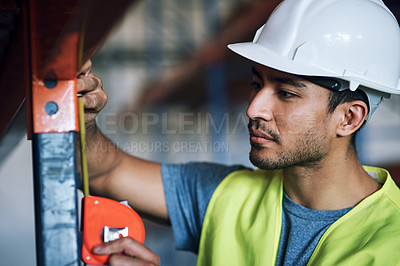 Buy stock photo Shot of a young builder using a measuring tape at a construction site