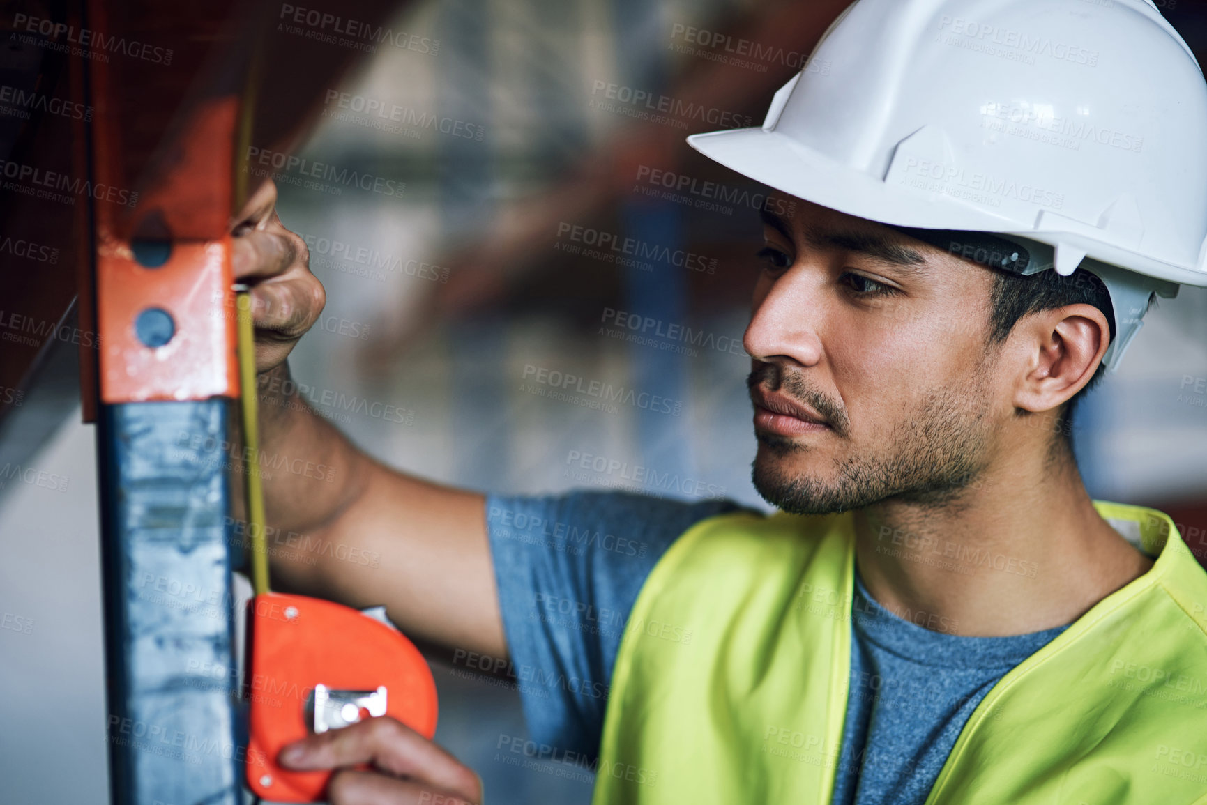 Buy stock photo Shot of a young builder using a measuring tape at a construction site