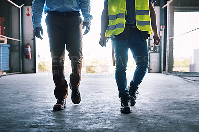 Buy stock photo Shot of two unrecognisable builders walking through a construction site