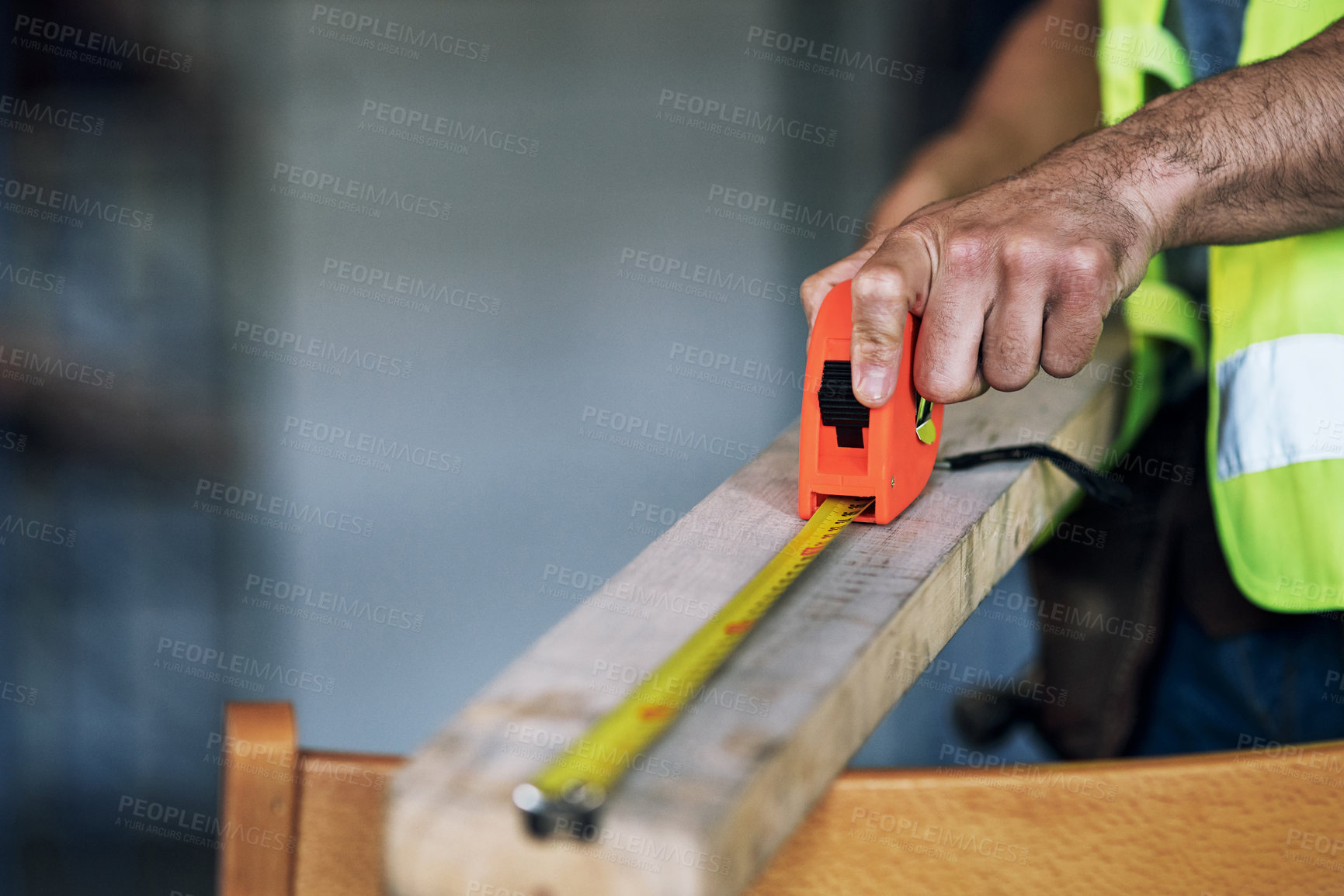 Buy stock photo Shot of a builder using a measuring tape at a construction site