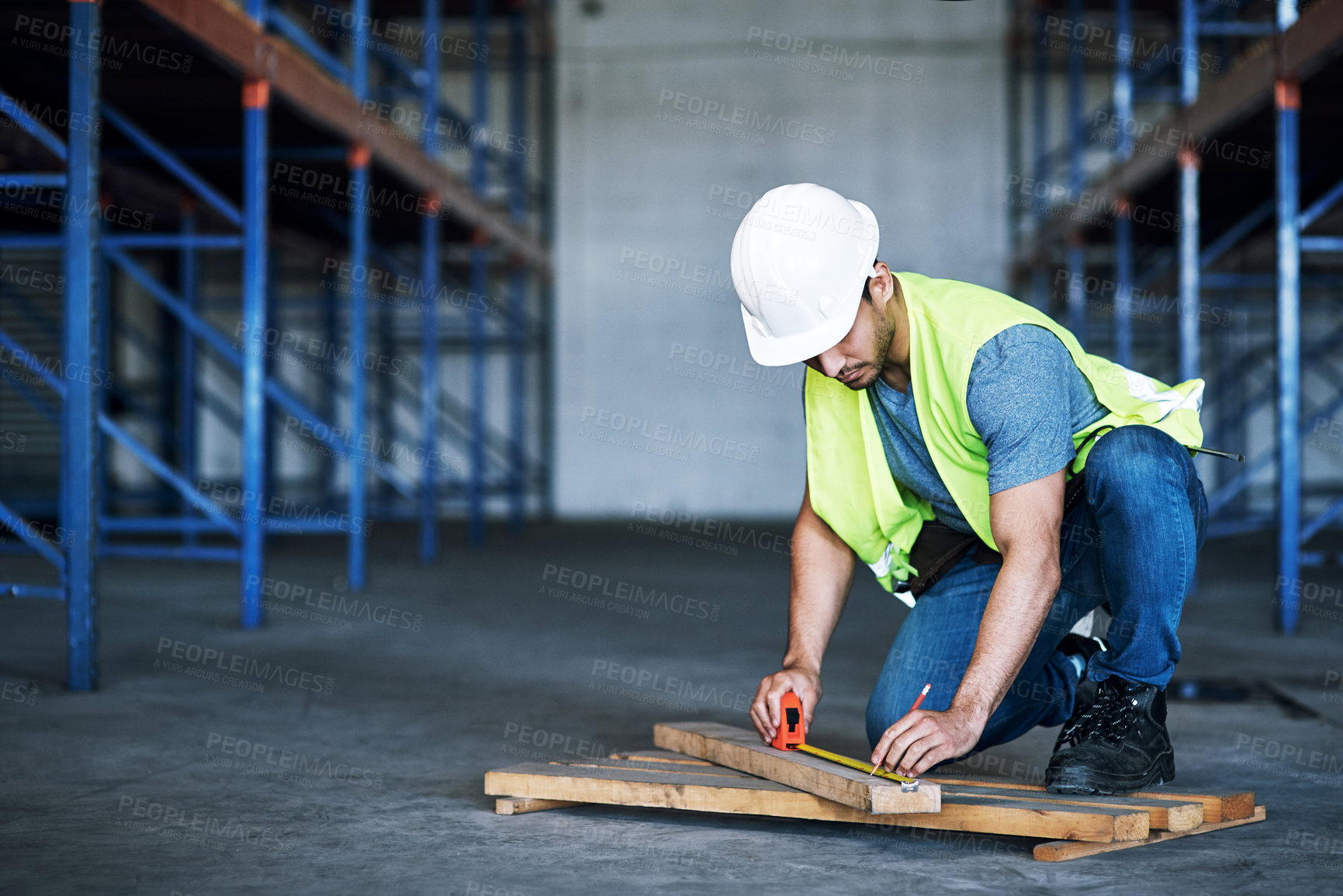 Buy stock photo Shot of a young builder using a measuring tape at a construction site