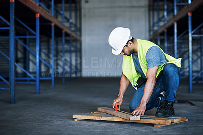 Buy stock photo Shot of a young builder using a measuring tape at a construction site