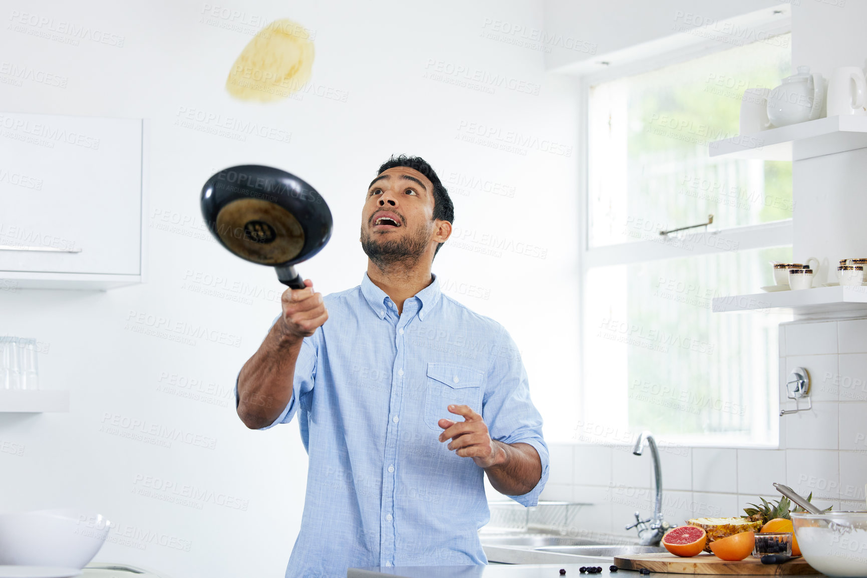 Buy stock photo Shot of a young man making pancakes at home