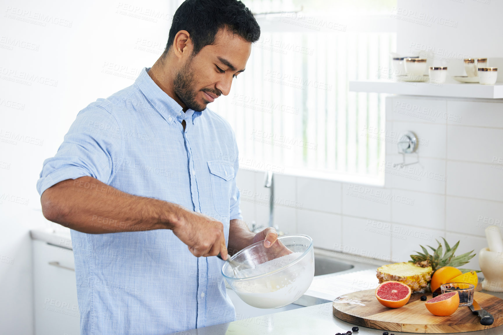 Buy stock photo Shot of a man making himself a smoothie at home