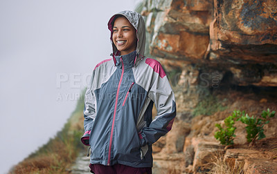 Buy stock photo Shot of a woman wearing her rain jacket while out hiking