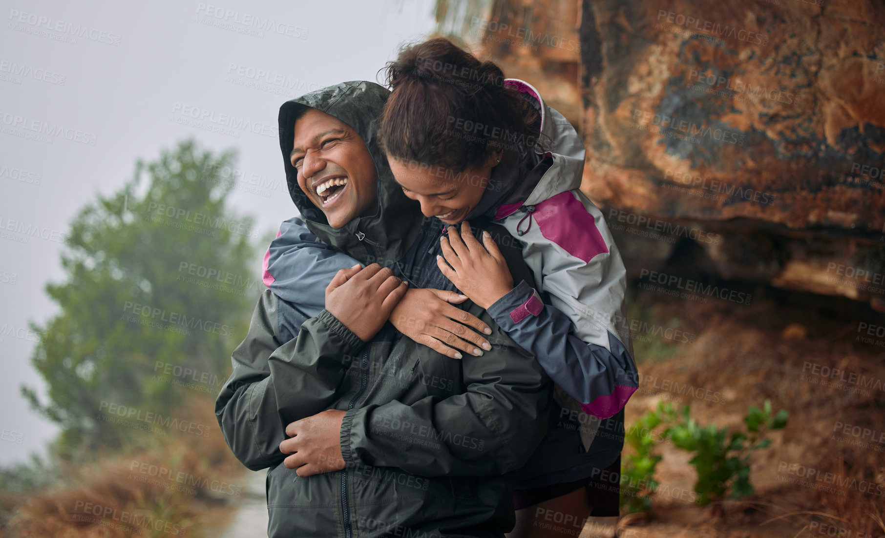 Buy stock photo Shot of a young couple wearing their rain jackets while out hiking