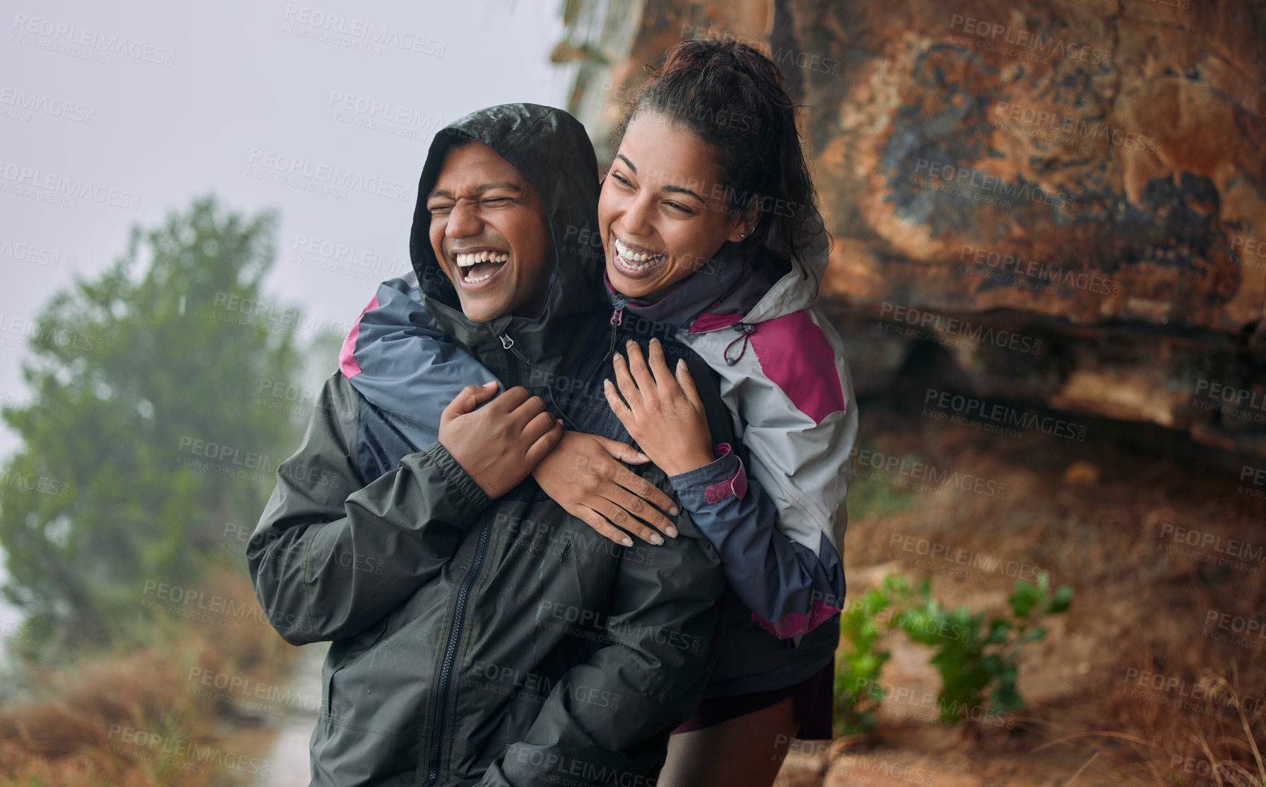 Buy stock photo Shot of a young couple wearing their rain jackets while out hiking