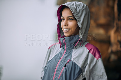 Buy stock photo Shot of a woman wearing her rain jacket while out hiking