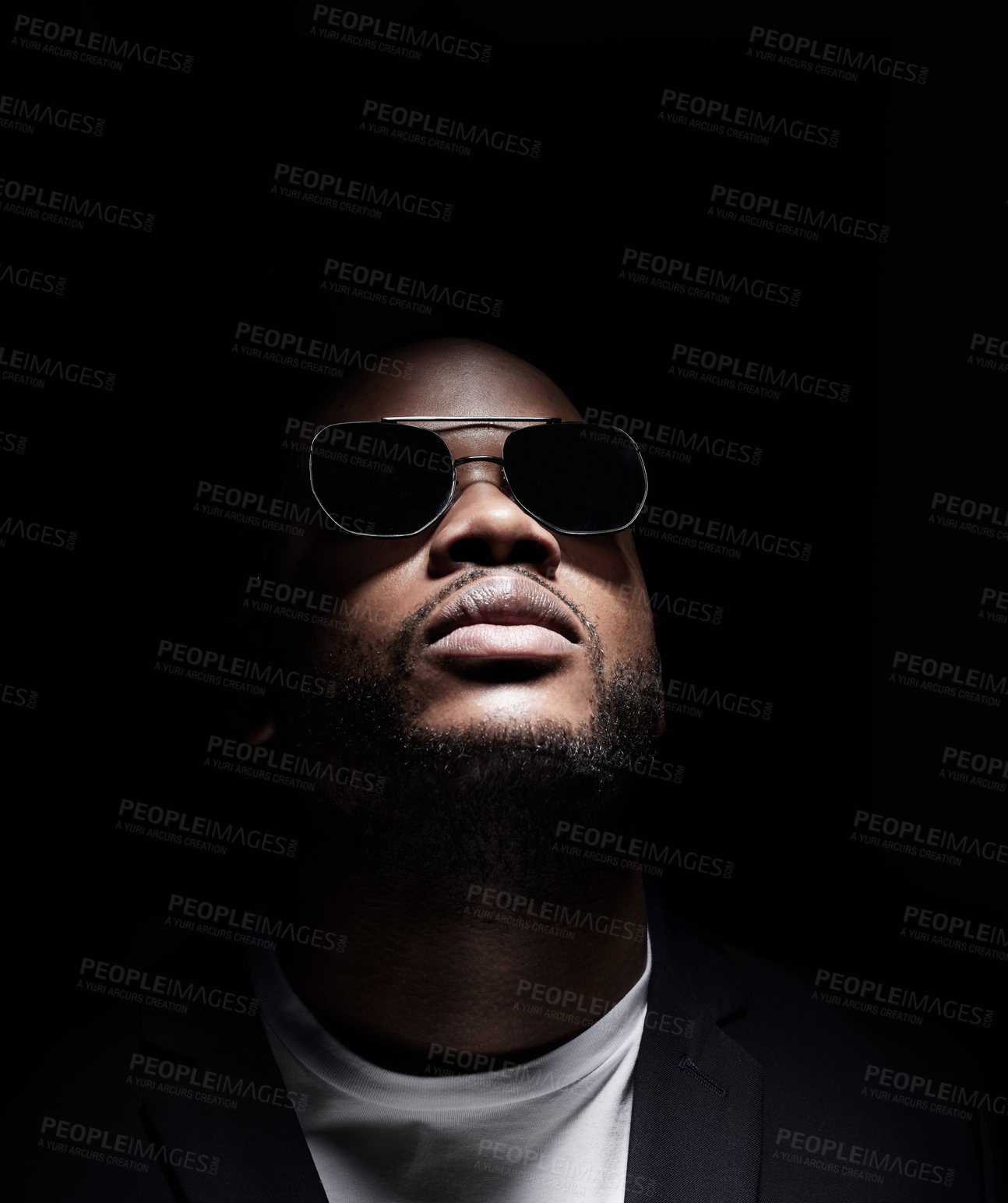 Buy stock photo Studio shot of a man wearing sunglasses while posing against a dark background