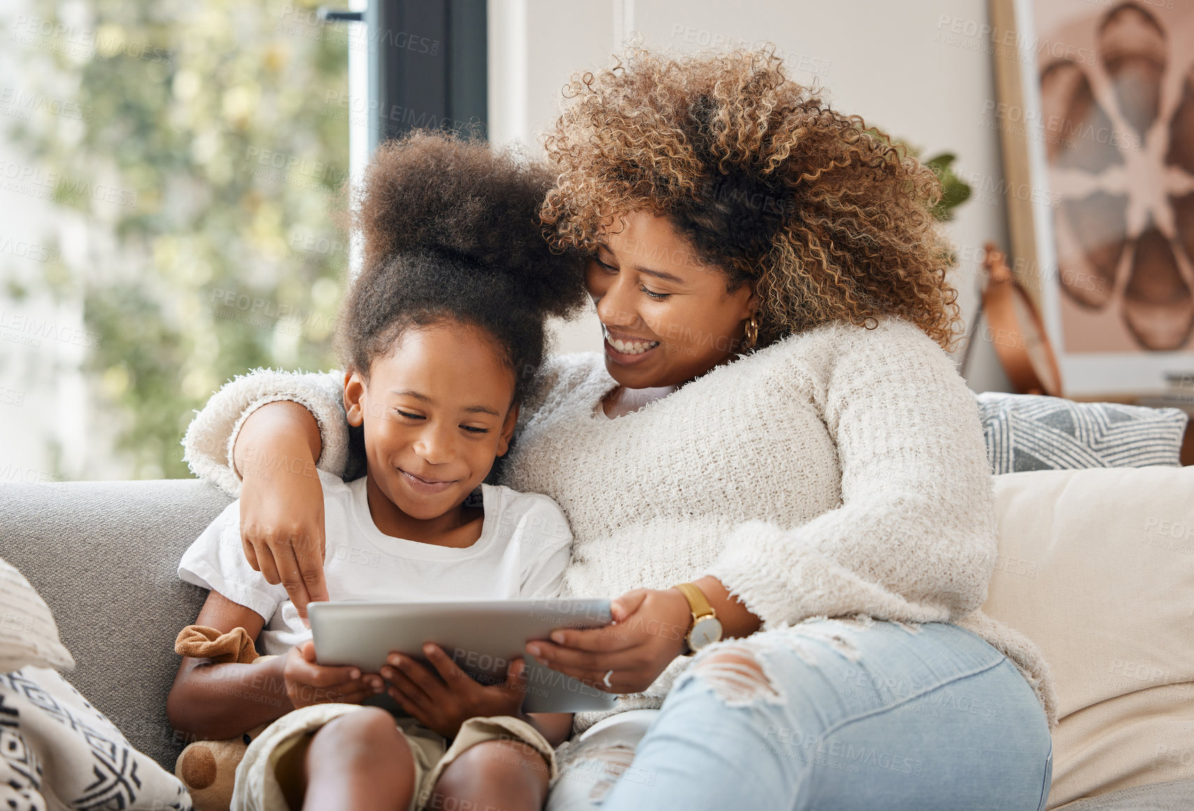 Buy stock photo Shot of a young mother using a digital tablet with her daughter at home