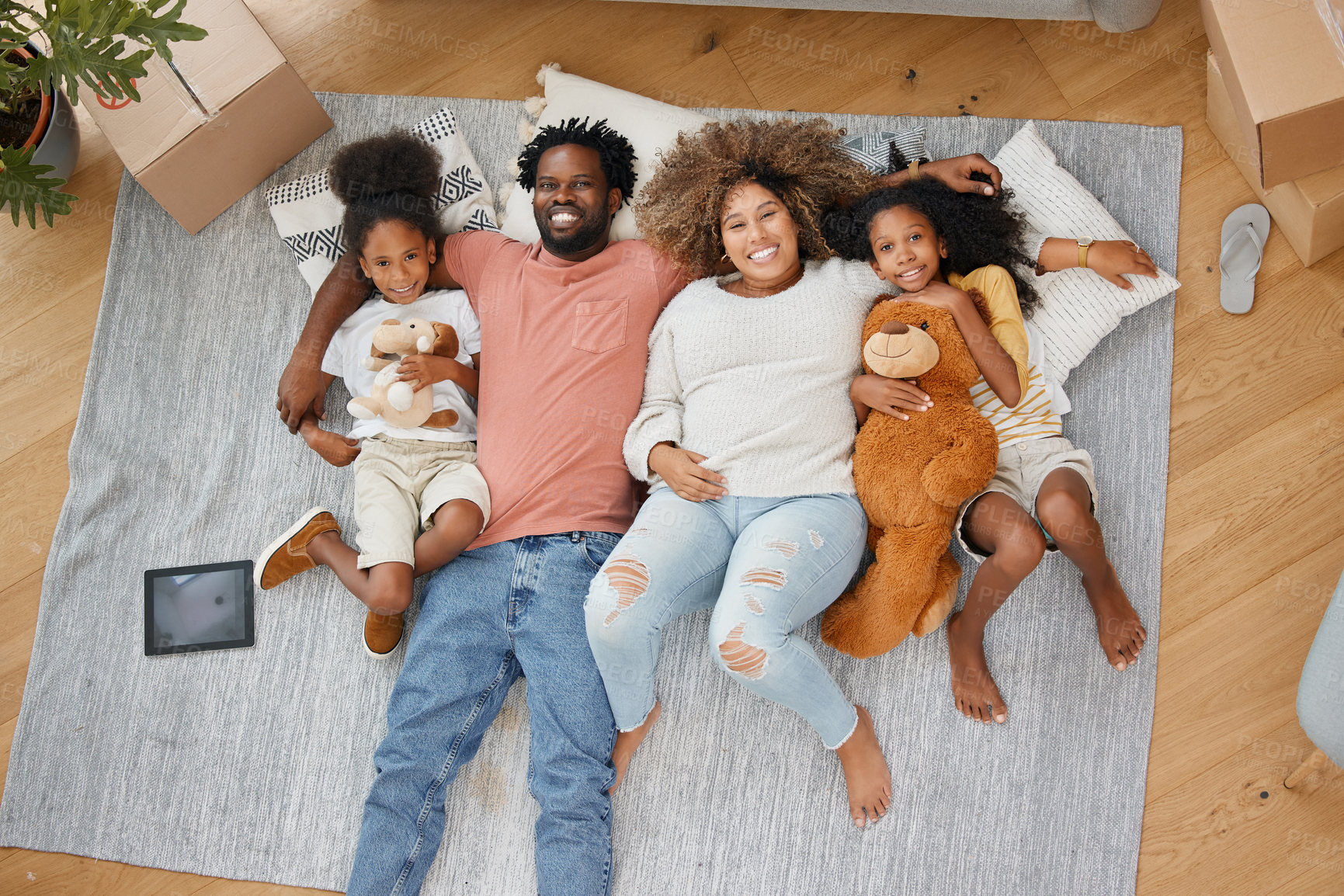 Buy stock photo Aerial shot of a young family lying on the floor at home