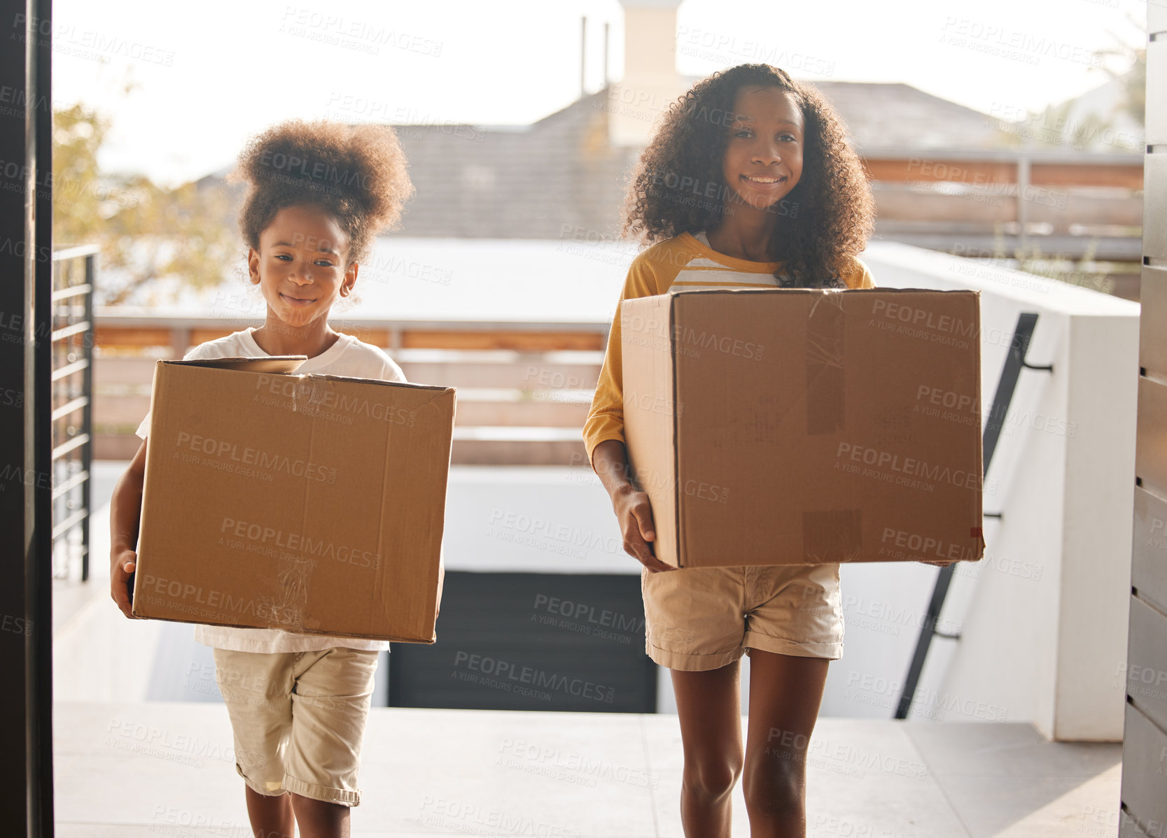 Buy stock photo Shot of two sisters carrying boxes into their new home