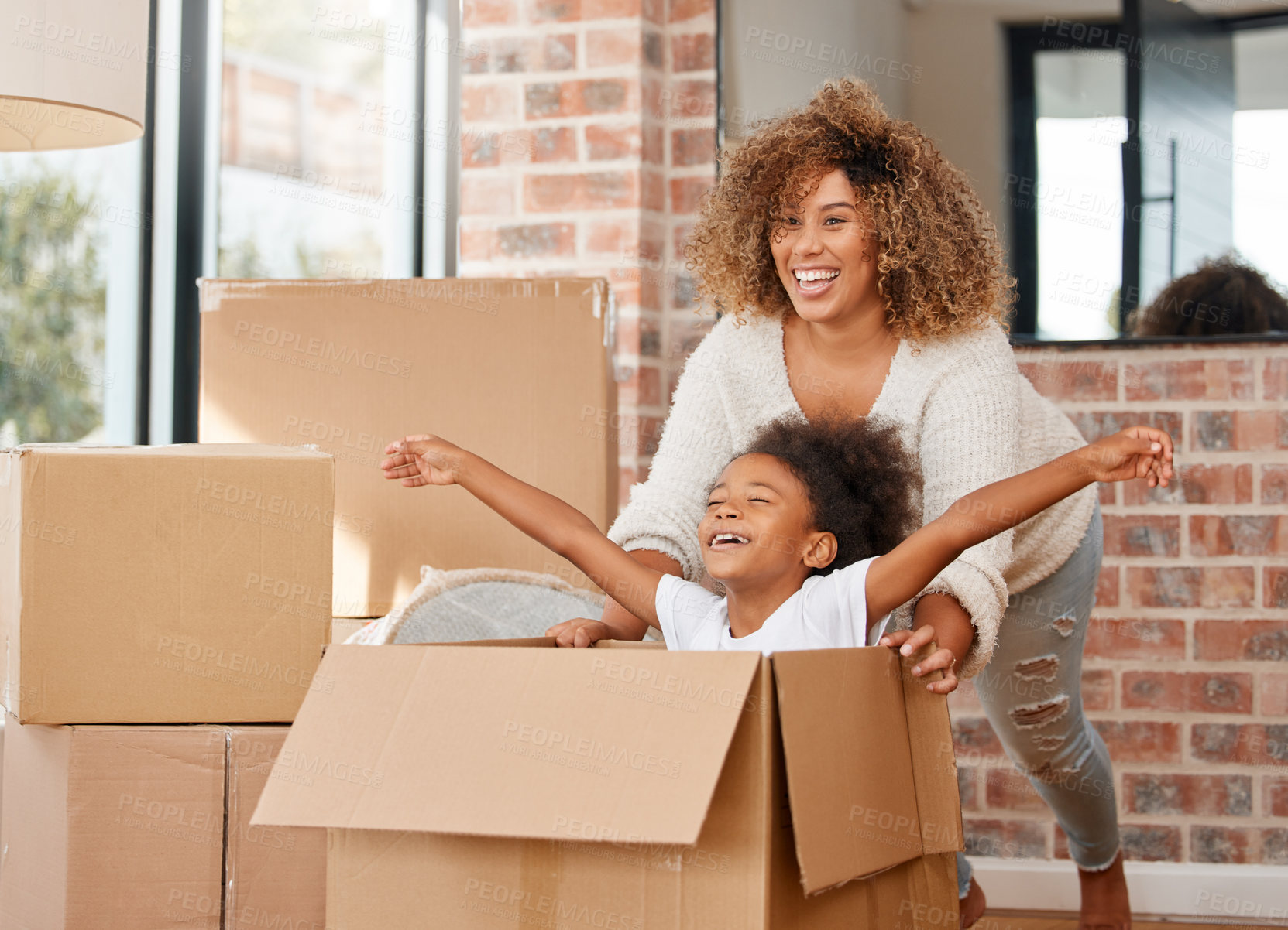 Buy stock photo shot of a mother pushing her daughter in a box at home