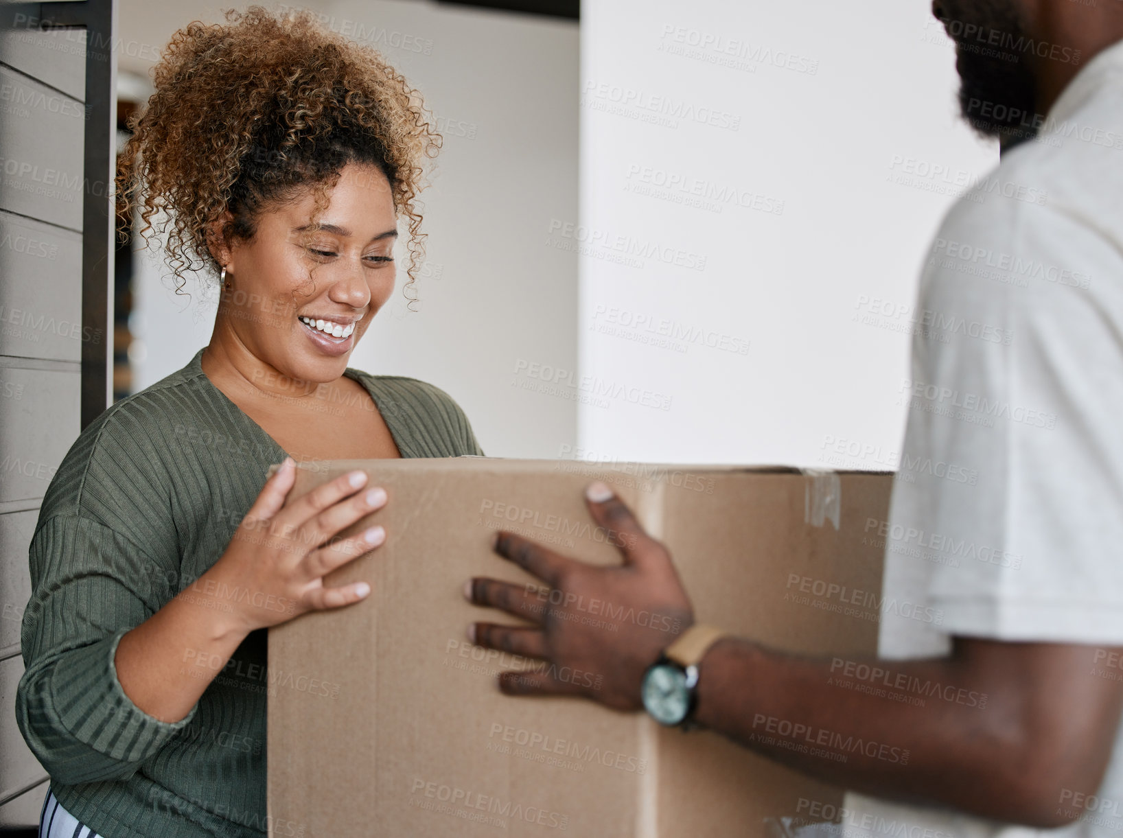 Buy stock photo Shot of a young woman receiving a box from a deliveryman at home