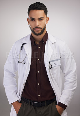 Buy stock photo Shot of a handsome young doctor standing alone in the studio