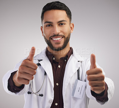 Buy stock photo Shot of a handsome young doctor standing alone in the studio and making a thumbs up hand gesture