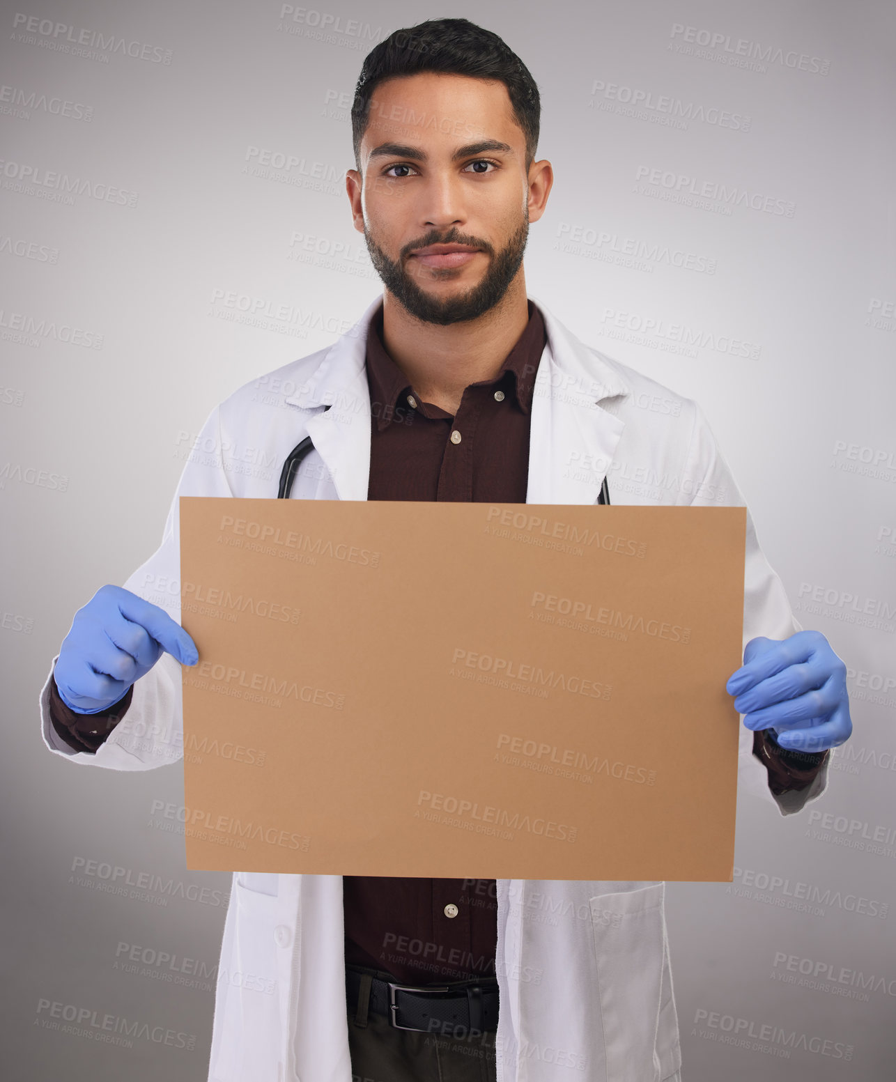 Buy stock photo Shot of a handsome young doctor standing alone in the studio and holding up a poster