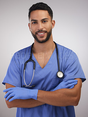 Buy stock photo Shot of a handsome young nurse standing alone in the studio with his arms folded