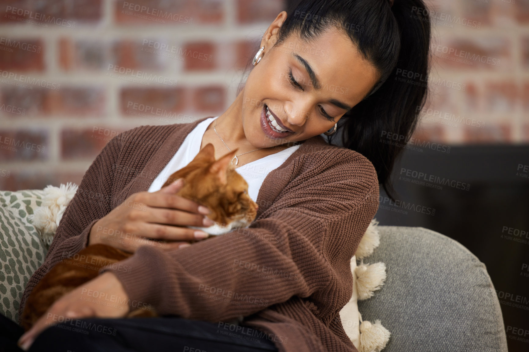 Buy stock photo Shot of a young woman bonding with her cat while sitting at home