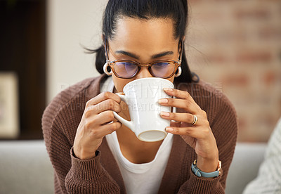 Buy stock photo Shot of a young woman wearing her glasses and drinking coffee while sitting at home
